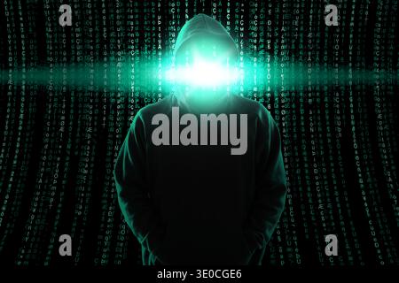 Cybercriminal in hood against programming code. Digital safety Stock Photo