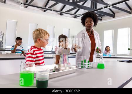 African American teacher with students showing experiment in school lab with test tubes, copy space Stock Photo