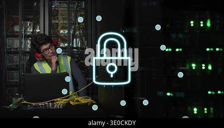 Securing Korean tech in hi-vis red-muffs working at rack, using laptop, yellow cables, lock overlay Stock Photo