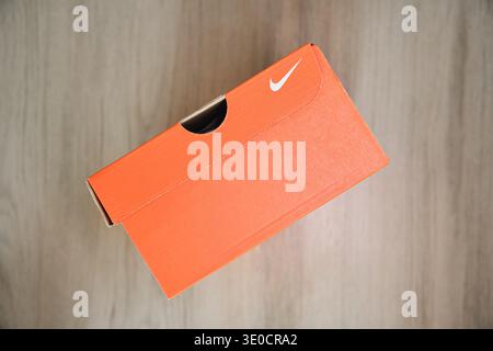 Nike shoebox in orange packaging with white swoosh logo on a wooden floor Stock Photo