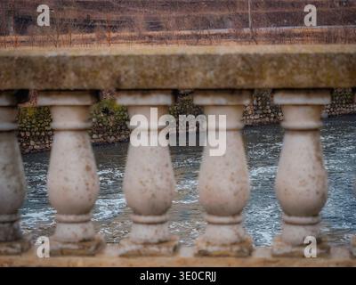 View of the Fox River from the Benton Street bridge in Aurora Illinois through concrete balusters of the bridge railing Stock Photo