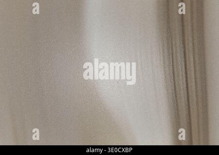 A blurry image showcasing a light beige textured surface with faint vertical lines and subtle shadow play creating a minimalist aesthetic. Stock Photo