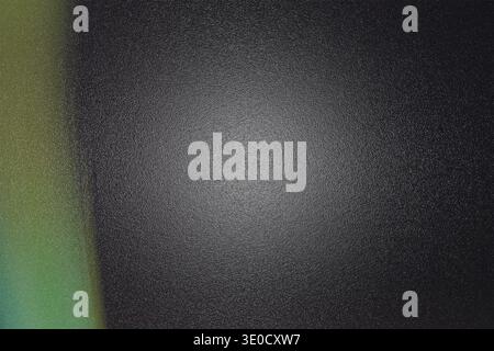 A dark gray textured background features a blurred, vertical light leak exhibiting a gradient of green and yellow hues on the left side. The overall e Stock Photo