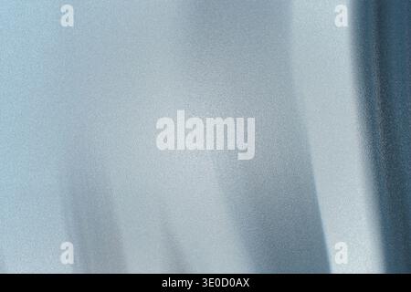 A close-up shot reveals the subtle texture and soft light blue hue of a draped fabric. The image features gentle folds and variations in light, creati Stock Photo