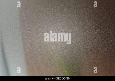 An out-of-focus photograph shows a textured, brownish-gray surface, possibly a wall or piece of furniture. A hint of green is visible in the bottom ri Stock Photo