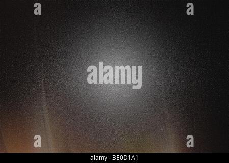 A dark abstract image featuring a bright, central glow surrounded by subtle radial light streaks and a textured, dark background. The overall effect i Stock Photo