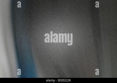A slightly out-of-focus image shows a dark gray surface with subtle texture and a hint of blue along the left edge. The lighting is uneven, creating a Stock Photo