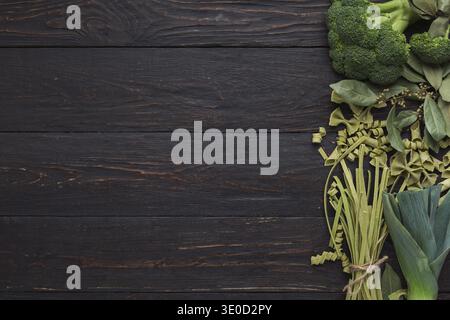 Green frame of pasta and vegetables on rustiv wooden background Stock Photo