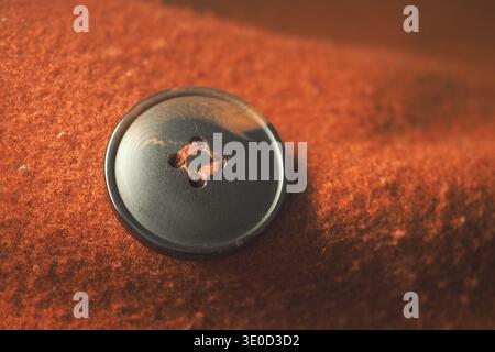 Black button on a brown fabric surface with soft texture Stock Photo