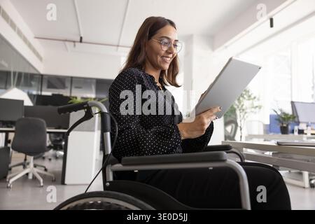 Positive female project manager in wheelchair using professional online service Stock Photo