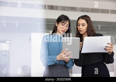 Asian manager woman showing content on tablet to colleague Stock Photo