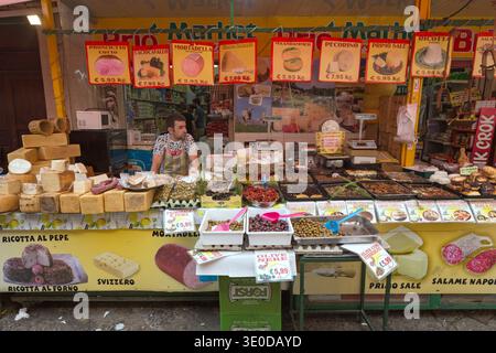 26.08.2018, Italy, Sicily, Palermo - Cheese sale at Mercato Vucciria. Behind a display of cheese wheels, olives, and other Italian specialties, a vend Stock Photo