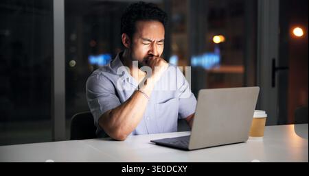 Night, man and yawn in office with laptop, journalist research and fatigue for news investigation. Late, tired person and writer in workplace with Stock Photo