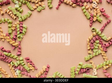 Frame of dried spiral pasta on pink background Stock Photo