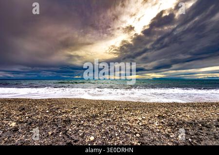 Dramatic evening seascape at Paralia Portaria beach in Chalkidiki, Central Macedonia, Greece. Dark storm clouds over the Thermaic Gulf with waves brea Stock Photo