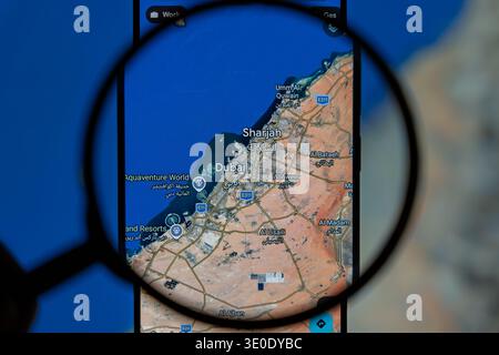 Magnifying glass over smartphone screen displaying map of Dubai and Sharjah UAE, travel planning and navigation concept on Google Maps Stock Photo