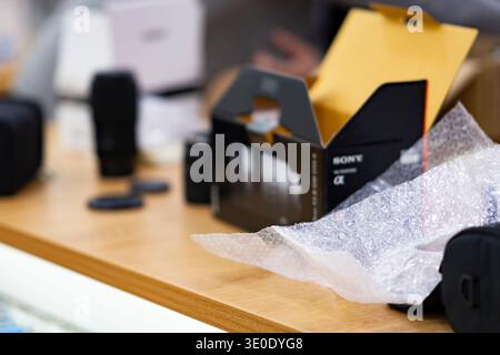 Sony Alpha camera box and accessories during unboxing on a wooden table. Modern photography equipment and technology concept Stock Photo