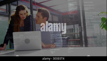 Working colleagues in blazer, blue shirt reviewing code on silver laptop at white table in office Stock Photo