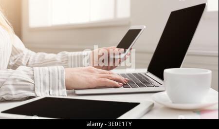 Woman manager working on laptop and holding phone Stock Photo