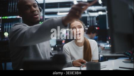 Diverse Professional Team Reviewing Investment Data in Global Brokerage Firm. Mentor Gestures Towards Advanced Financial Indices, Woman Engages in Discussion. Concept of Synergy of Multicultural Team. Stock Photo