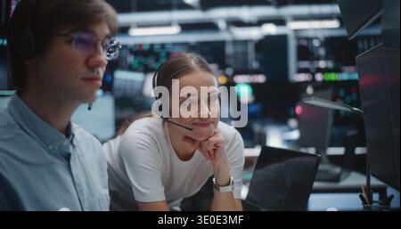 Male and Female Brokers Analyzing Real Time Stock Data Together. Two Professional Investment Experts Collaborate Closely on Trading Floor. Strategy Discussion, Data Driven Decision Making, Teamwork. Stock Photo