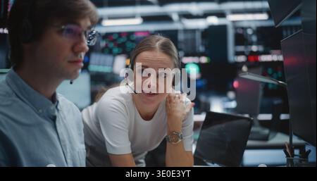 Male and Female Brokers Analyzing Real Time Stock Data Together. Two Professional Investment Experts Collaborate Closely on Trading Floor. Strategy Discussion, Data Driven Decision Making, Teamwork. Stock Photo