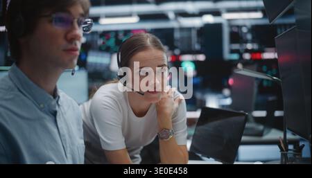 Male and Female Brokers Analyzing Real Time Stock Data Together. Two Professional Investment Experts Collaborate Closely on Trading Floor. Strategy Discussion, Data Driven Decision Making, Teamwork. Stock Photo