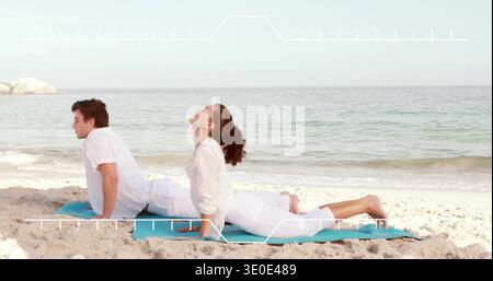 Stretching couple doing back-bends on sandy shoreline with turquoise mat, wearing light clothing Stock Photo