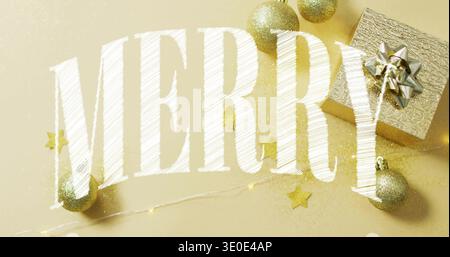 Displaying large white 'MERRY' lettering on gold tabletop with gold baubles, present, string lights Stock Photo