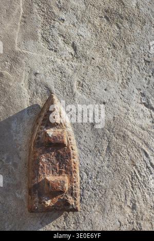 Vertical shot of an old cast-iron flatiron, vintage smoothing tool on concrete. Stock Photo