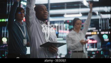 Multicultural Team of Professional Traders Standing in Active Trading Pit, Simultaneously Gesture, Shouts Orders, and Checks Their Tablets. Concept Synchronized Teamwork and Rapid Crisis Management. Stock Photo