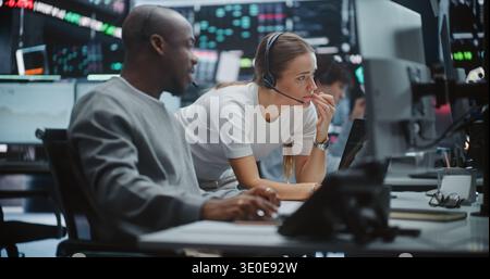 Two Professional Brokers Analyzing Big Data Trends on Multi Monitor Dashboard. Man Gestures Towards Specific Chart on Monitors While Woman Provides Input. Strategic Planning in Modern Fintech Office. Stock Photo