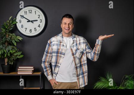 Cheerful man presenting something with hand standing in modern office interior Stock Photo