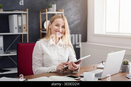 Cheerful young woman using her touchpad in office Stock Photo