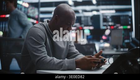 Focused African American Male Trader Executing Urgent Order Via Smartphone. Man Uses Mobile App Execute Critical Trade or Monitor Asset Prices. Speed Mobile Technology in Modern Financial Markets. Stock Photo