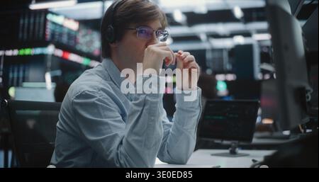 Focused Young Broker Scrutinizing Market Data on Tablet in Trading Office. Tech Savvy Male Analyst in Blue Shirt, Engaged With Analytical Tools on Tablet in Stock Exchange. Advanced Data Analysis. Stock Photo