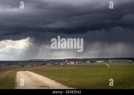 Wetter in Baden-Württemberg, Mit den ersten kräftigen Gewittern des Jahres hat sich das Wetter im Nördlinger Ries am Mittwoch deutlich verändert. Über Dischingen Landkreis Heidenheim zogen am Nachmittag dunkle, teils spektakuläre Gewitterwolken auf, begleitet von kurzen, aber intensiven Schauern. Neben Regen gingen örtlich auch Graupelschauer nieder. Die markanten Wolkenformationen sorgten dabei für eindrucksvolle Himmelsbilder über der Landschaft. Das wechselhafte Frühlingswetter brachte innerhalb kurzer Zeit einen deutlichen Temperatur- und Wetterumschwung. Die ersten Gewitter der Saison sin Stock Photo