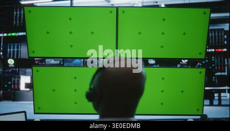 African American Male Trader Working at Modern High Tech Desk With Four Green Screen Monitors in Busy Financial Office. Concept of Financial Data, Software Demos, and Corporate Presentations. Stock Photo