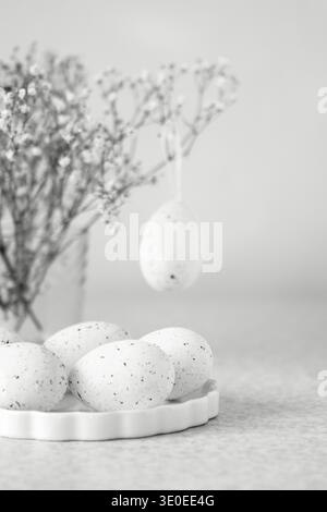 Speckled Easter egg still life with dried gypsophila and hanging ornament on ceramic plate Stock Photo