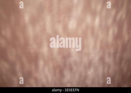 Soft pink wall with abstract light reflection and textured plaster surface creating subtle pattern and mood Stock Photo