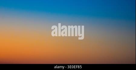 Intense contrast in the evening sky showing heavy dark blue clouds and a powerful fiery orange light at the distant horizon. Stock Photo