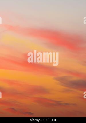 Close-up of a fiery sunset sky showing intense horizontal layers of glowing orange, yellow, and red clouds during dusk. Stock Photo
