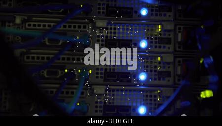 Displaying rack-mounted server blades inside server rack, showing teal Ethernet cables and LEDs Stock Photo