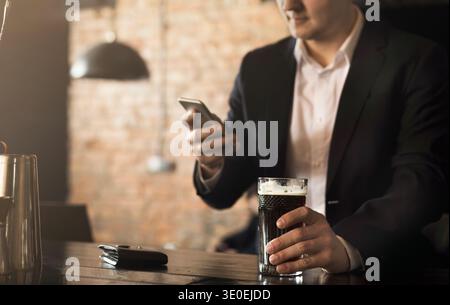 Young man sitting at bar counter and using smartphone Stock Photo