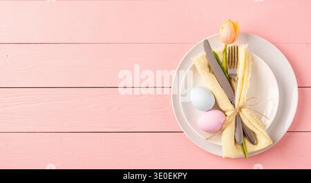 Happy Easter. Table setting for Easter feast. Easter eggs, tulips and cutlery top view flat lay on pink rustic background Stock Photo