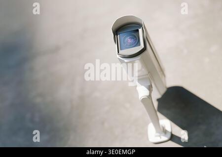 Modern outdoor white security camera mounted on a wall, providing surveillance and protection. High-tech CCTV system for safety, monitoring, and crime Stock Photo