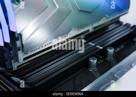 Detailed macro of high-speed DDR RAM modules installed in a motherboard. Premium memory sticks with metal heat sinks and RGB glow, representing PC har Stock Photo