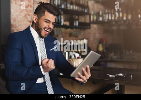Euphoric businessman winning and watching at tablet Stock Photo