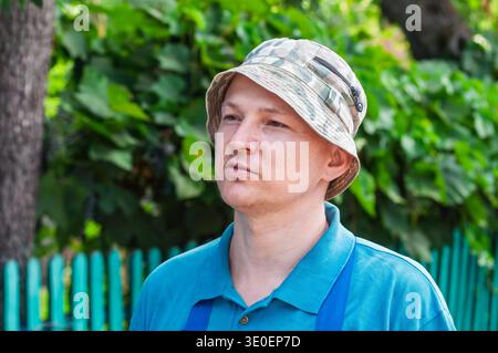 Man in camouflage bucket hat looking off to the side on a sunny day Stock Photo