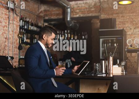Young man sitting at bar counter and using digital tablet Stock Photo